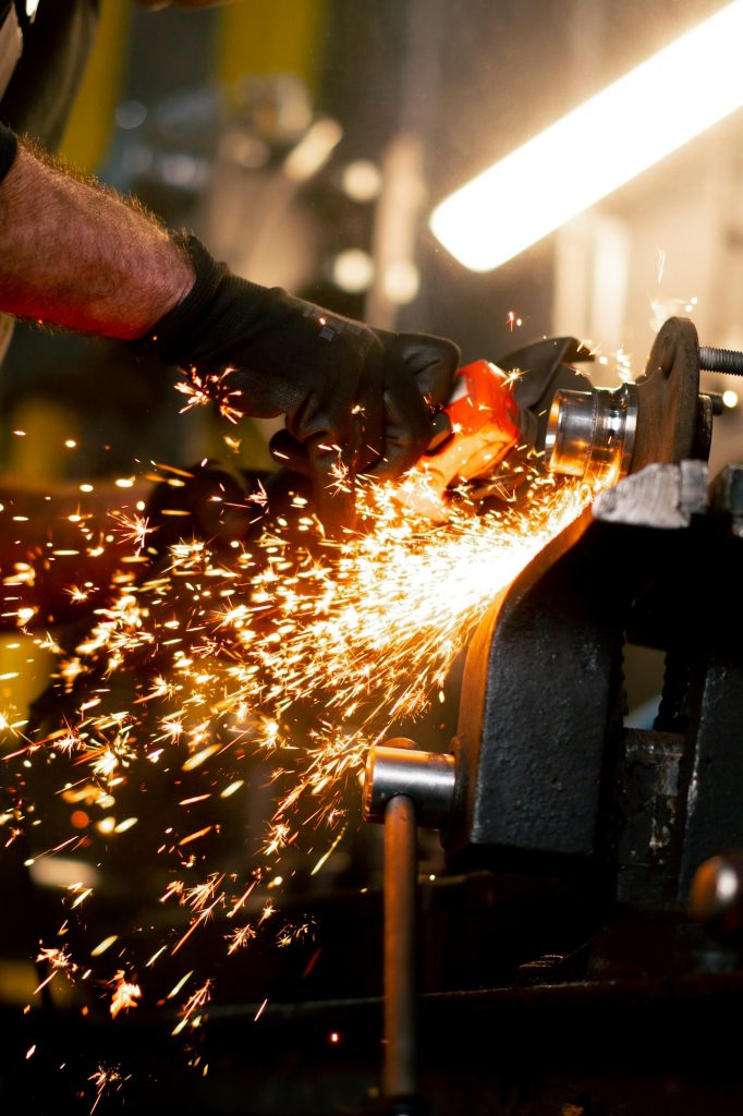 close-up of car mechanic working at a service station with an angle grinder from which sparks fly