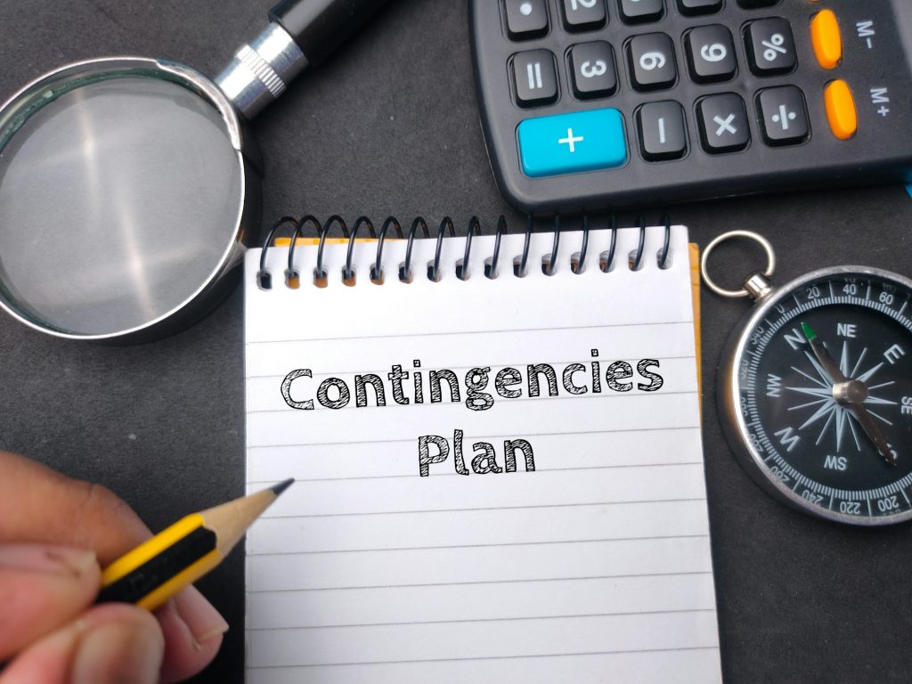 Hamd holding pencil wriiten on notebook with the word Contingencies Plan. Business concept.