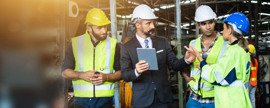 Industrial engineer and businessman in safety helmet working in factory, planning training workers